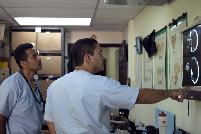 El doctor Saúl Quijada y el técnico Raymundo Sánchez estudian la radiografía de un cráneo para descartar improntas de bala como causa de muerte.