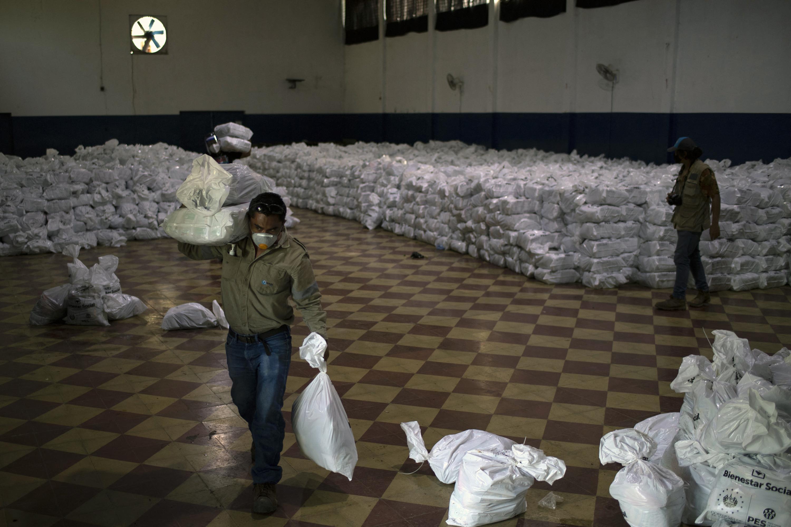 Un trabajador de la Empresa Salvadoreña de Transmisión de Energía ETESAL, carga paquetes alimentarios en el centro de acopio y distribución de la ciudad de Santa Ana, El Salvador, el 1 de julio de 2020. Foto de El Faro: Yuri Cortez/AFP.