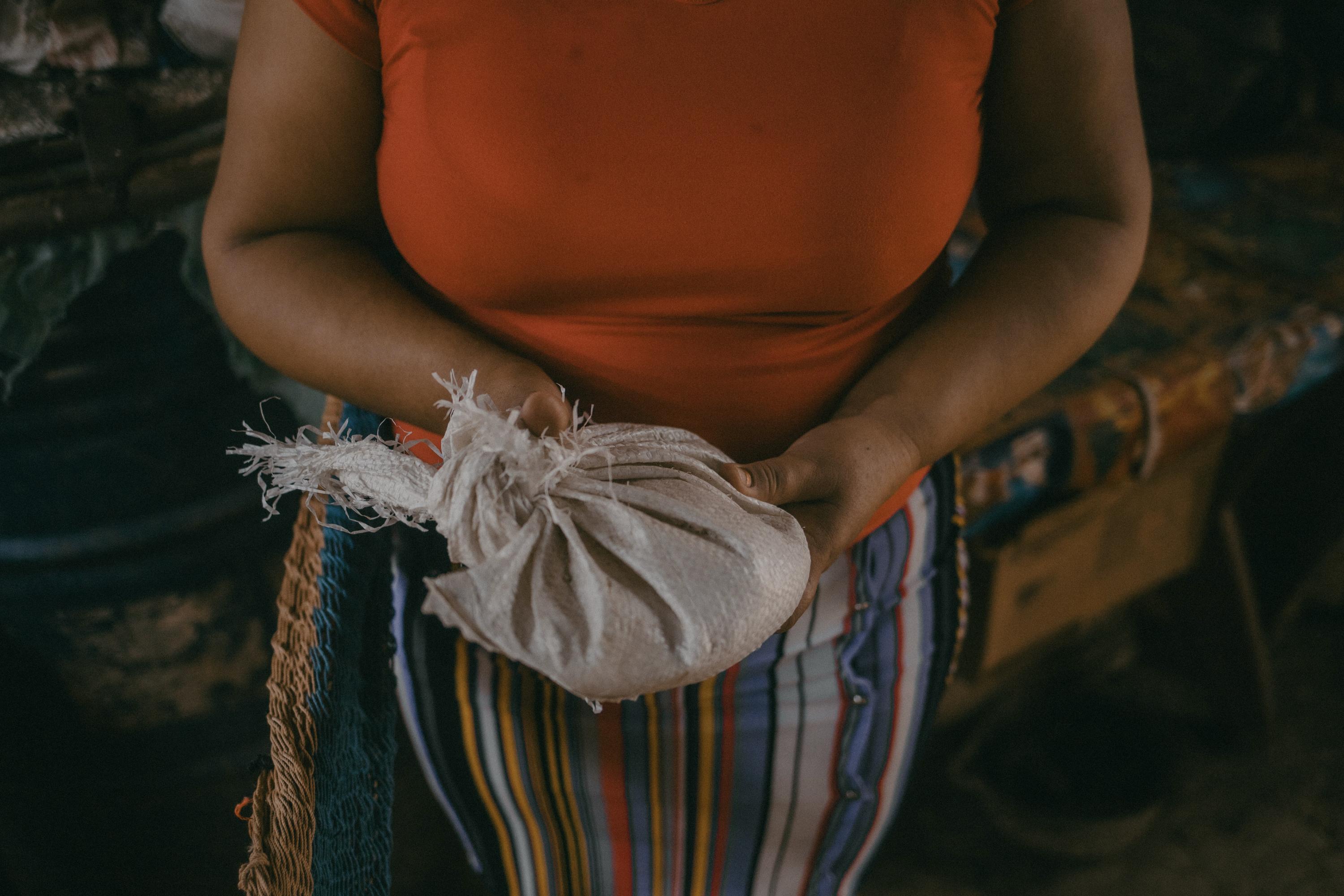 Ana holds the small amount of rice that remains from a donation her family received a few months ago. Apart from the rice, her pantry contains some cooking oil and a milk carton filled with sugar. Photo Carlos Barrera