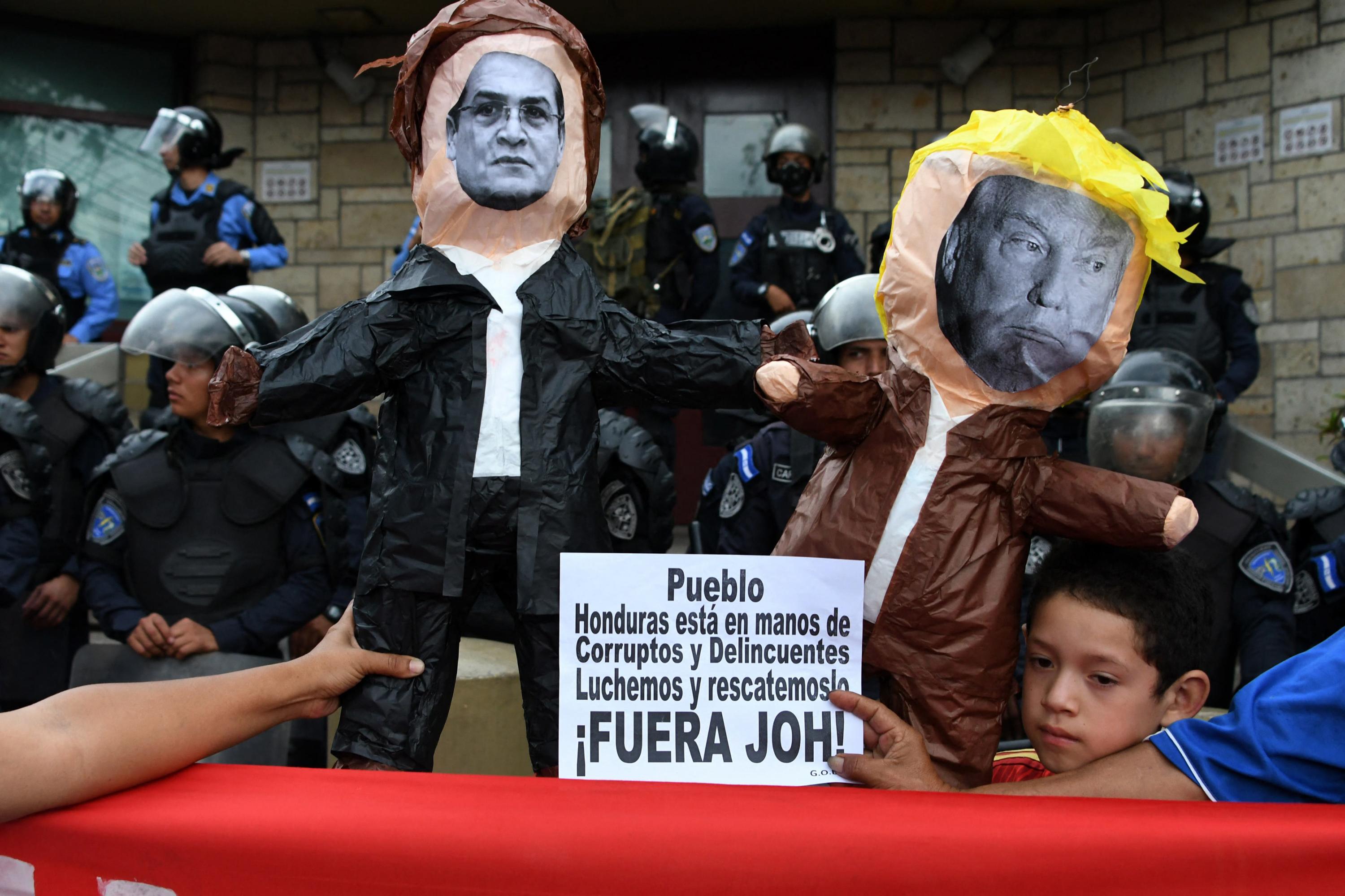 Simpatizantes de la Alianza de Oposición Hondureña Contra la Dictadura y del partido LIBRE intentan prender fuego a dos muñecos que representan al presidente estadounidense Donald Trump y al presidente hondureño Juan Orlando Hernández, durante protestas frente a la embajada de Estados Unidos en Tegucigalpa. Foto de El Faro: Orlando Sierra/ AFP.