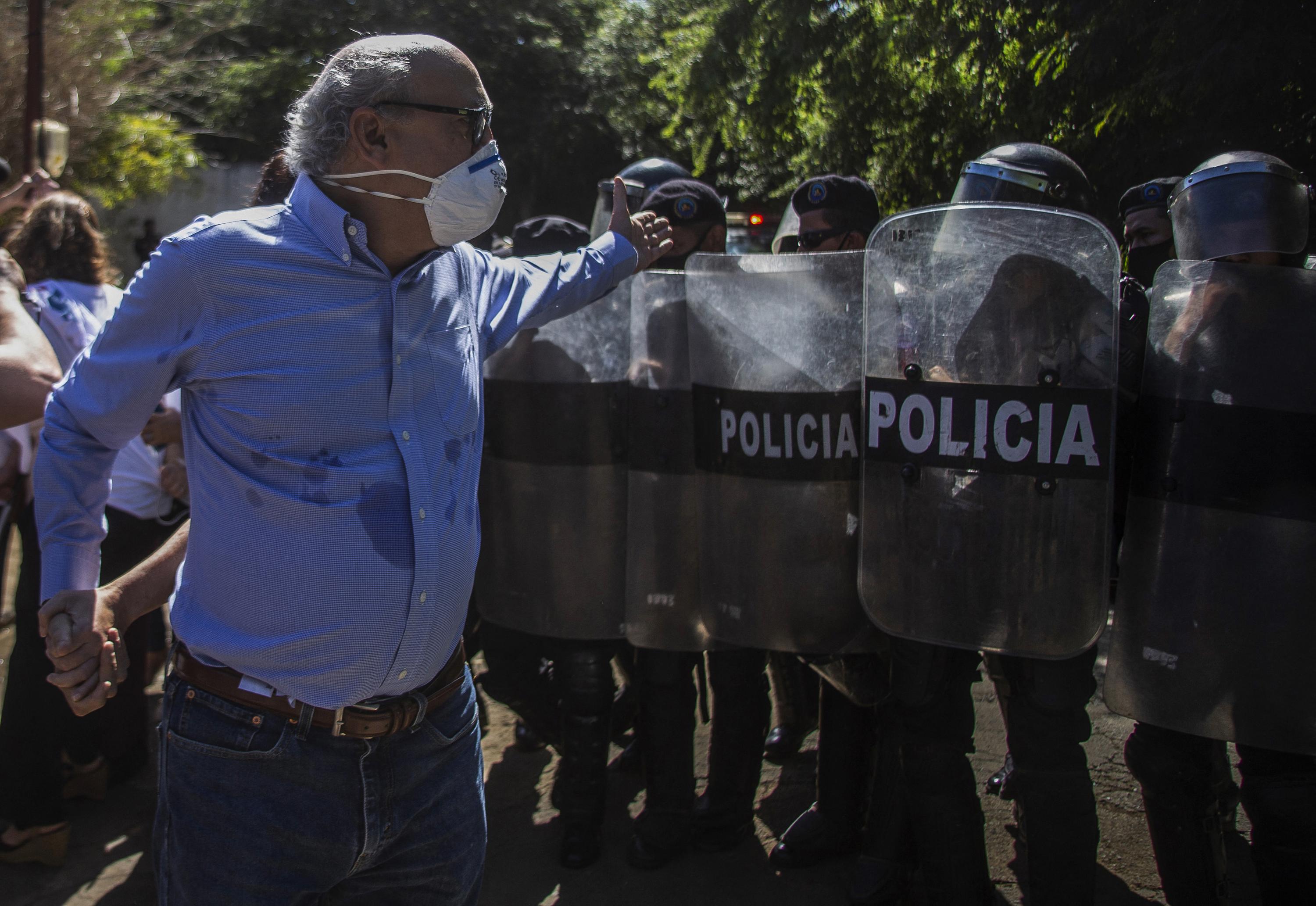 El periodista nicaragüense Carlos Fernando Chamorro, director de El Confidencial y del programa televisivo Esta Semana, es empujado por agentes antidisturbios el 14 de diciembre de 2020 frente a las oficinas de El Confidencial en Managua, confiscadas dos años antes por el régimen del presidente Daniel Ortega. Foto de El Faro: AFP.