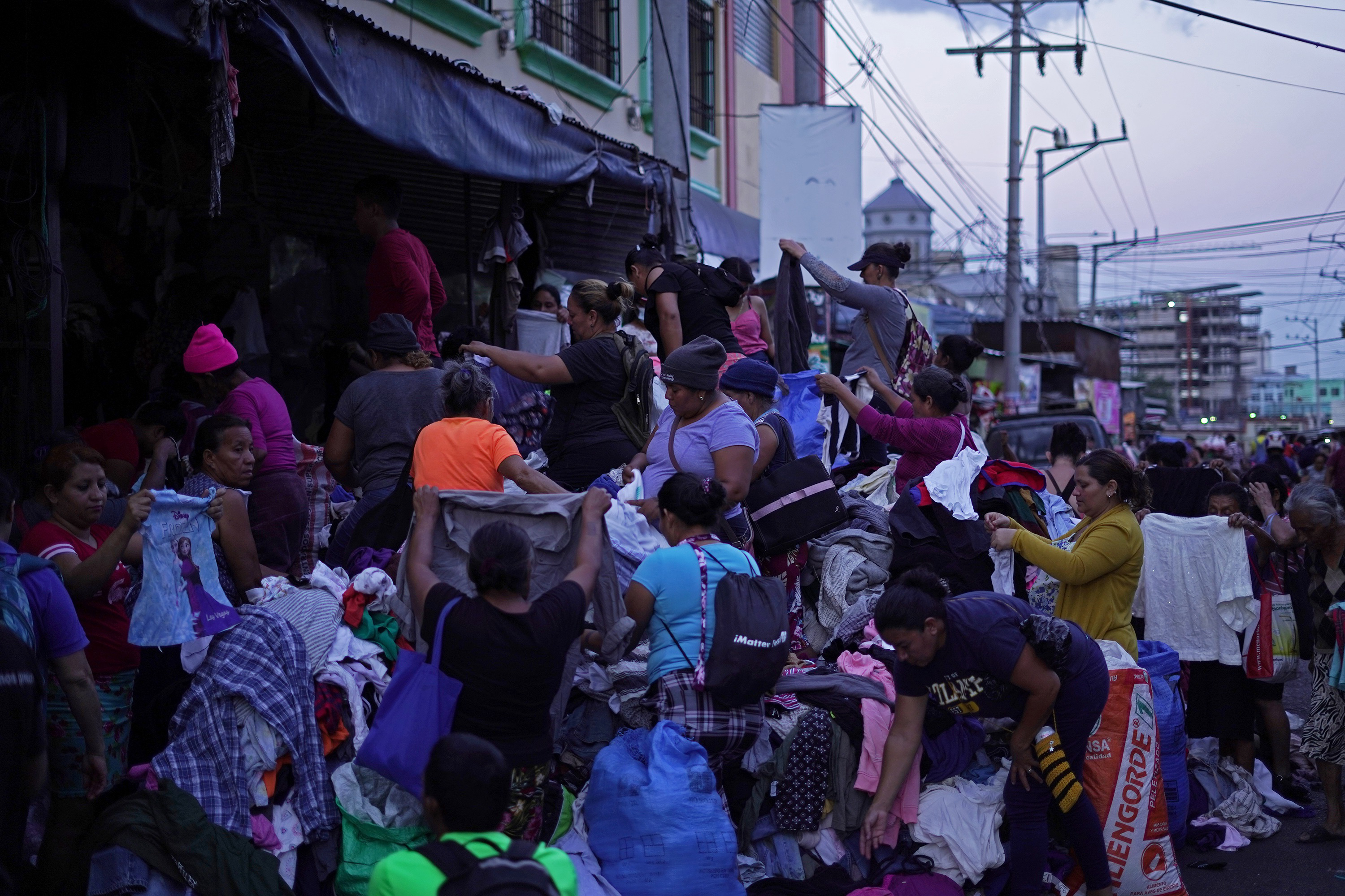 Compradores se agolpan alrededor de un puesto de reventa de ropa usada en la calle Gerardo Barrios de San Salvador en abril de 2023. El puestro es uno de los pocos que sobrevivieron al desalojo forzado impuesto por la alcaldía de la capital días antes. Foto El Faro: Víctor Peña