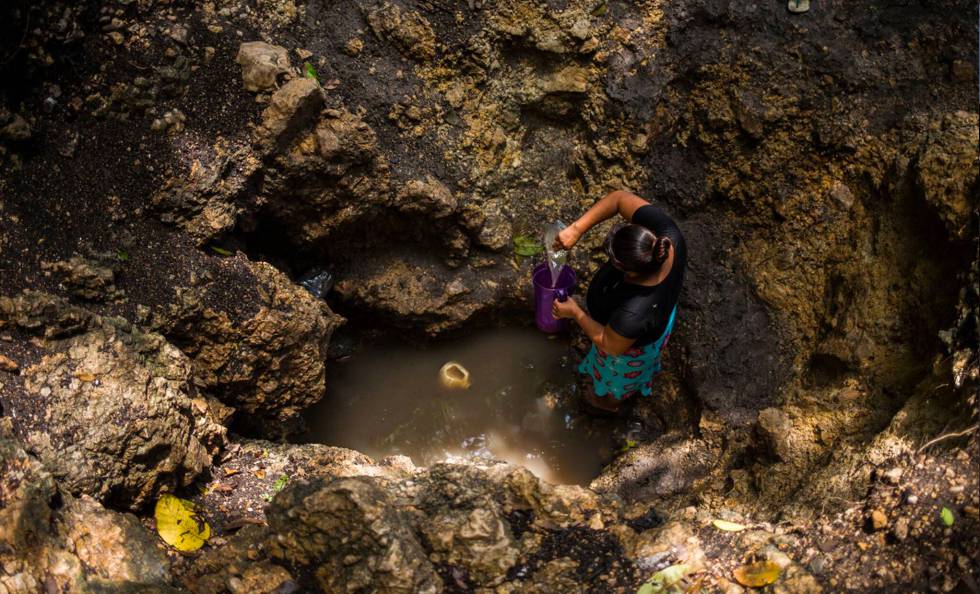 Yolanda López saca agua de un agujero